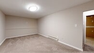 Located at 1200 Charleston Green in Malvern, PA, this basement-level space offers a practical and versatile layout spread across a comfortable footprint. The space is divided into distinct areas, each serving a different purpose and stage of finish.

The finished basement room is a standout feature, presenting neutral beige carpet, smooth white walls, and clean white baseboards that create a bright and welcoming atmosphere. A flush-mount ceiling light provides even illumination throughout the space. A baseboard heating unit runs along the lower wall, ensuring year-round comfort. The room's clean, move-in-ready condition makes it well-suited for use as a bedroom, home office, or recreation room.

The second basement area remains unfinished, exposing the structural wood-framed ceiling, concrete flooring, and visible utility elements including a water heater and plumbing. Partially drywalled walls indicate that finishing work is already underway, offering significant potential for customization or additional living space. This area also includes a door providing access to an adjacent room.

A staircase connects the basement level to the rest of the residence, tying the layout together. An additional unclassified room rounds out the space, adding further flexibility.

Overall, this space presents a functional combination of finished comfort and unfinished potential, ideal for those looking to personalize and expand their usable square footage.