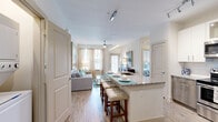 Located at 4320 Commons Dr W in Destin, Florida, this thoughtfully designed 2-bedroom, 2-bathroom residence offers a bright, coastal-inspired interior across a single, well-organized floor. The open-concept living area seamlessly connects the kitchen, dining, and living spaces, creating a flowing, sociable layout. The kitchen is a standout feature, boasting white shaker cabinetry, two-tone lower cabinetry accents, a classic subway tile backsplash, granite countertops, stainless steel appliances, and a large kitchen island with bar seating — ideal for both casual dining and entertaining. Light wood-style flooring runs throughout the main living areas, enhancing the airy ambiance. Natural light pours in through multiple windows dressed with sheer curtains. Both bedrooms are carpeted and fitted with ceiling fans, offering a comfortable retreat. The primary bedroom includes a walk-in closet and an en-suite bathroom featuring granite countertops, a wood-toned vanity, and a tiled shower. The second bathroom mirrors the same quality finishes, with a shower-tub combination. Additional conveniences include a dedicated laundry area, pantry, and four closets for generous storage. A private patio completes this well-appointed Destin residence.