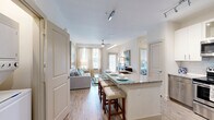 Located at 4320 Commons Dr W in Destin, Florida, this thoughtfully designed 2-bedroom, 2-bathroom residence offers a bright, coastal-inspired interior across a single, well-organized floor. The open-concept living area seamlessly connects the kitchen, dining, and living spaces, creating a flowing, sociable layout. The kitchen is a standout feature, boasting white shaker cabinetry, two-tone lower cabinetry accents, a classic subway tile backsplash, granite countertops, stainless steel appliances, and a large kitchen island with bar seating — ideal for both casual dining and entertaining. Light wood-style flooring runs throughout the main living areas, enhancing the airy ambiance. Natural light pours in through multiple windows dressed with sheer curtains. Both bedrooms are carpeted and fitted with ceiling fans, offering a comfortable retreat. The primary bedroom includes a walk-in closet and an en-suite bathroom featuring granite countertops, a wood-toned vanity, and a tiled shower. The second bathroom mirrors the same quality finishes, with a shower-tub combination. Additional conveniences include a dedicated laundry area, pantry, and four closets for generous storage. A private patio completes this well-appointed Destin residence.