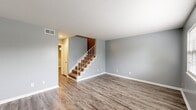 This two-story home at 2103 Nottingham Way in Albany, Georgia, offers a practical and well-organized layout divided evenly between two floors. The main level houses the living room, dining room, and kitchen, all unified by durable wood-look flooring and soft gray walls with crisp white baseboards. The living area is open and airy, anchored by a carpeted staircase with a white-railed banister that leads to the upper level. The kitchen features white cabinetry with brushed nickel hardware, stone-patterned countertops, and a range, providing functional workspace for everyday cooking.

Upstairs, the two bedrooms are finished with wall-to-wall carpet and ceiling fans, creating comfortable retreats. The primary bedroom offers a generous footprint with a dedicated closet. Both bathrooms are clean and functional; the bathrooms include tiled tub-shower combinations with white subway-style tile surrounds. Three closets are distributed throughout the home, providing ample storage. The consistent cool gray color palette and white trim carry through every room, lending a cohesive, neutral aesthetic suited to a variety of décor styles.