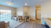 Located in East Bethel, Minnesota, this single-floor unit offers a well-designed layout that balances comfort and functionality. The open-concept living area features a combination of durable wood-look flooring and plush carpeting, with warm neutral walls that create a bright, welcoming atmosphere. A large window allows ample natural light to fill the space, offering views of the surrounding area. The living room flows seamlessly into a dining nook, providing a versatile area for relaxing and entertaining.

The kitchen is thoughtfully appointed with rich dark-stained cabinetry, granite-style countertops, stainless steel appliances including a full-size refrigerator and electric range, and a double-basin sink. Recessed lighting overhead enhances the clean, modern aesthetic of the space.

A dedicated den or office room offers a quiet retreat, complete with carpeted flooring, a window with natural light, and enough space for a desk and seating area—ideal for remote work or personal use.

The full bathroom is well-appointed with a tub and shower combination, a large vanity mirror, ample countertop space, and a dark-toned vanity cabinet. Neutral tile flooring completes the space with a clean, timeless look.

Throughout the unit, consistent trim work, flush-mount lighting, and a cohesive neutral color palette contribute to a polished, move-in-ready feel.