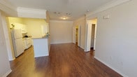 This single-story residence offers a thoughtfully designed layout across three bedrooms and two full bathrooms. The open living area serves as the heart of the home, featuring rich dark wood-style flooring, crown molding, and a ceiling fan overhead. Large front-facing windows allow ample natural light to fill the space, creating a bright and welcoming atmosphere. The living area flows seamlessly into the kitchen via a half-wall breakfast bar, making it ideal for both everyday living and entertaining.

The galley-style kitchen is efficiently designed with white cabinetry extending to the ceiling, light-toned countertops, a double basin sink, and white appliances including a refrigerator, electric range, and built-in microwave. The wood-style flooring continues throughout the kitchen, maintaining a cohesive look.

Each of the three bedrooms features plush carpeting, ceiling fans with integrated lighting, and ample closet space, including a walk-in closet in one room. The bedrooms offer a quiet retreat, with windows providing outdoor views. Both bathrooms are clean and functional — one includes a tub-shower combo with white tile surround, while the second features a shower with a vanity and light countertop. The overall ambiance is neutral, clean, and move-in ready.