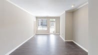 This single-story residence is designed with a neutral, contemporary aesthetic throughout. The open-concept living area features dark hardwood-style flooring, crown molding, and large windows with exterior door access that invite abundant natural light, creating a bright and airy atmosphere.

The kitchen is well-equipped with white cabinetry, light granite-style countertops, and a full suite of stainless steel appliances including a range, microwave, and refrigerator. A central island provides additional prep and workspace, while dark hardwood-style flooring continues from the living area, reinforcing a cohesive design.

The bedrooms feature plush carpeting and ceiling fans for added comfort. Each bedroom connects to a bathroom with white vanity cabinetry, white countertops, a soaking tub, and a shower. One bathroom features a brushed nickel multi-bulb vanity light fixture above a wide mirror, offering ample illumination. Bedroom closets include wire shelving systems, maximizing storage capacity.

Throughout the residence, warm beige and taupe wall tones complement the white trim and cabinetry, lending a clean, cohesive look. The overall layout, as indicated by the 3D scan, flows efficiently between living, dining, kitchen, and bedroom spaces.