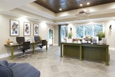 Located in Acworth, Georgia, this single-story community clubhouse at Stanton Place offers a thoughtfully designed gathering space that blends functionality with contemporary style. The main entry opens into a bright, airy reception and leasing area distinguished by soaring vaulted ceilings, large windows dressed with teal drapery, and large-format tile flooring laid in a herringbone-inspired pattern throughout. Natural light pours in through multiple windows, creating an inviting and open atmosphere.

The expansive lounge and common area serves as the heart of the clubhouse, featuring a coffered ceiling section with a dramatic dark wood finish, pendant lighting fixtures, and a mounted flat-screen television. Comfortable seating arrangements — including armchairs, sofas, and accent rugs — provide residents with versatile spaces to relax or socialize. Vibrant abstract artwork adorns the walls, adding a bold, creative character to the interior.

A dedicated business center offers dual workstations equipped with computers and a printer, complemented by a trio of framed abstract art pieces above. A bar-height communal table positioned beside large sliding glass doors frames a picturesque view of the outdoor pool and lush surrounding greenery, seamlessly connecting the interior to the resort-style amenities just beyond.