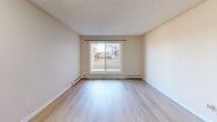 This 2-bedroom, 2-bathroom residence in Edmonton, Alberta offers a practical and comfortable single-floor layout designed for everyday living. Light wood laminate flooring runs throughout the unit, lending a clean, cohesive look to every room. The open-plan living and kitchen area provides a generous shared space, with the kitchen featuring dark cabinetry, black appliances, and a functional countertop layout. Natural light filters into the living area through a large sliding window with views of the surrounding neighbourhood. The spacious primary bedroom includes mirrored sliding closet doors that enhance the sense of space, and connects conveniently to an en-suite bathroom with a walk-in shower and beige countertop vanity. The second bedroom is well-proportioned, also benefiting from a window with natural light and baseboard heating. The second bathroom features a full soaker tub and shower combination, a large vanity mirror with overhead lighting, and a dark wood cabinet vanity. Both bedrooms have dedicated closets. Textured ceilings are consistent throughout, and the neutral warm-beige palette creates a calm, move-in-ready ambiance. Baseboard heating is present across multiple rooms, ensuring year-round comfort.