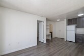 Located at 1225 East Grand Avenue in Escondido, CA, this efficiently designed one-bedroom, one-bathroom residence offers a well-organized single-level floor plan. The open-concept living area seamlessly integrates the dining room, kitchen, and living room into one cohesive space, maximizing functionality. Wood-look plank flooring runs throughout, complementing the neutral, light-toned walls and textured ceilings that lend a clean, modern aesthetic.

The kitchen is well-appointed with rich, dark brown cabinetry, light countertops, a stainless steel sink, and white appliances including a coil-top range with hood and a full-size refrigerator — providing ample storage and prep space relative to the unit's scale.

The bedroom is a bright, serene retreat featuring a window dressed with vertical blinds that invite natural light while offering privacy. A dedicated closet adds practical storage, and the space is finished with the same warm wood-look flooring found throughout.

The bathroom is neatly designed with a vanity featuring matching dark cabinetry, a light countertop, and a full tub-shower combination with grab bars. A hallway connects the main living areas to the private spaces.

Sliding glass doors from the living area open to a private patio surrounded by lush greenery, bringing natural light and an inviting outdoor connection to this thoughtfully laid-out Escondido residence.