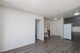 Located at 1225 East Grand Avenue in Escondido, CA, this efficiently designed one-bedroom, one-bathroom residence offers a well-organized single-level floor plan. The open-concept living area seamlessly integrates the dining room, kitchen, and living room into one cohesive space, maximizing functionality. Wood-look plank flooring runs throughout, complementing the neutral, light-toned walls and textured ceilings that lend a clean, modern aesthetic.

The kitchen is well-appointed with rich, dark brown cabinetry, light countertops, a stainless steel sink, and white appliances including a coil-top range with hood and a full-size refrigerator — providing ample storage and prep space relative to the unit's scale.

The bedroom is a bright, serene retreat featuring a window dressed with vertical blinds that invite natural light while offering privacy. A dedicated closet adds practical storage, and the space is finished with the same warm wood-look flooring found throughout.

The bathroom is neatly designed with a vanity featuring matching dark cabinetry, a light countertop, and a full tub-shower combination with grab bars. A hallway connects the main living areas to the private spaces.

Sliding glass doors from the living area open to a private patio surrounded by lush greenery, bringing natural light and an inviting outdoor connection to this thoughtfully laid-out Escondido residence.