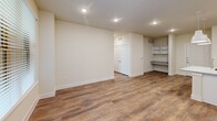 Located in Dallas, TX, this two-bedroom, two-bathroom residence offers a thoughtfully designed single-floor layout with a clean, contemporary aesthetic. The open-concept kitchen and living area serves as the heart of the home, showcasing crisp white shaker cabinetry reaching to the ceiling, granite countertops, a spacious center island with an undermount sink, and stainless steel appliances including a French door refrigerator, slide-in range, and built-in microwave. Stylish pendant lighting anchors the kitchen space, while warm wood-style flooring flows seamlessly throughout the entire unit. The living area benefits from natural light through large windows with blinds and provides access to an exterior door. Both bedrooms are generously proportioned, with the primary bedroom offering a dedicated closet with built-in shelving and rods. Each bathroom features granite-topped vanities with white cabinetry, and one includes a full tub-shower combination with white tile surround. A second full bathroom offers a dual-sink vanity and a separate shower. Additional highlights include a built-in desk nook with granite surface, open shelving, a walk-in closet with multi-tier shelving, and recessed lighting throughout, contributing to a bright and functional living environment.