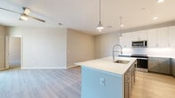 Located at 123 E Corporate Pl in Chandler, AZ, this well-appointed 2-bedroom, 2-bathroom residence offers a thoughtfully designed single-floor layout with modern finishes throughout. The open-concept kitchen and living area serves as the heart of the home, featuring a large center island with a white quartz countertop, a stainless steel pull-down faucet, and an undermount sink. Two-toned cabinetry — white upper cabinets paired with slate-gray lower cabinets — adds a contemporary contrast, while stainless steel appliances, including a gas range, microwave, and refrigerator, complete the kitchen. Pendant lighting illuminates the island, and light wood-style flooring extends throughout the main living areas. The living room opens to a private balcony through a floor-to-ceiling sliding glass door, inviting natural light and outdoor views. Both bedrooms are carpeted and include ceiling fans and windows with exterior views. The spacious primary bedroom connects to its own bathroom and features a generous walk-in closet with built-in shelving and double hanging rods. The bathrooms are finished with large-format tile surrounds in the tub-shower combinations and gray vanity cabinetry with white countertops, maintaining a clean and cohesive aesthetic throughout.
