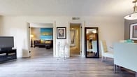 Located at 1300 Adams Ave in Costa Mesa, California, this well-appointed one-bedroom, one-bathroom residence offers a thoughtfully designed single-floor layout. The living room greets you with warm yellow accent walls, wood-style flooring, and a large sliding glass door that invites natural light and connects to the outdoors. The adjacent dining area flows naturally into a galley-style kitchen outfitted with warm wood cabinetry, granite-look countertops, and white appliances, creating a functional and cohesive space. A central hallway connects the main living areas to the private quarters, lined with additional wood-style flooring throughout. The generously sized primary bedroom features plush carpeting, multiple windows overlooking lush greenery, and a dedicated walk-in closet with built-in shelving. The full bathroom is appointed with wood-toned cabinetry, granite-look countertops, and large mirrors that enhance the sense of space. A separate area off the hallway with wood-style flooring offers versatility as a home office or flex space. Textured ceilings are present throughout, and the overall ambiance is bright, comfortable, and functional — ideal for those seeking a well-organized living space in Costa Mesa.