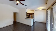 This single-story, one-bedroom, one-bathroom home in Conroe, TX offers a well-designed layout with a cohesive blend of modern finishes and functional living spaces. The open living area features vaulted ceilings, dark hardwood-style flooring, and a ceiling fan, creating an airy and comfortable atmosphere. Natural light flows in through a set of double French doors fitted with blinds, which open to the outdoors, alongside an additional side window. Built-in shelving flanks the French doors, providing convenient storage and display space. The kitchen is designed for efficiency, featuring a galley-style layout with rich dark cabinetry, granite countertops, stainless steel appliances including a refrigerator, range, and dishwasher, and a peninsula that connects seamlessly to the living area. The bedroom is a calm retreat finished with plush carpeting, a ceiling fan, and a window that allows in natural light. The bathroom includes a full tub and shower combination with large-format tile surround, tile flooring, and brushed nickel fixtures. Throughout the home, consistent flooring, neutral tones, and thoughtful detailing contribute to a clean, modern aesthetic.