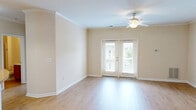 Located at 3800 Waterside Dr in Elizabeth City, NC, this single-floor 2-bedroom, 2-bathroom residence offers a practical and comfortable layout with consistent finishes throughout. The living room features warm hardwood-style flooring, crown molding, a ceiling fan with light fixture, and a set of French doors that invite natural light and provide outdoor access. The kitchen is well-equipped with rich cherry wood cabinetry, light stone-toned countertops, black appliances including a range, microwave, and dishwasher, and a curved peninsula with pendant lighting overhead — seamlessly connecting to the living area. Both bedrooms are carpeted and feature ceiling fans, windows with natural light, and closets. The primary bedroom is generously sized with its own dedicated closet space. The two bathrooms are finished with hardwood-style flooring and warm wood vanity cabinetry. One bathroom features a tub-shower combination, while the other offers a glass-enclosed stand-up shower. A dedicated closet provides additional storage. Neutral wall tones throughout the home create a clean, cohesive aesthetic that adapts well to a variety of interior styles.
