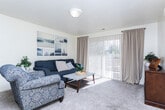 Located at 9300 S Redwood Rd in West Jordan, Utah, this thoughtfully laid-out 2-bedroom, 2-bathroom single-floor home offers a comfortable and functional living environment. The living room serves as the heart of the home, featuring plush carpeting, neutral walls, and a large sliding glass door dressed with sheer vertical blinds that invite abundant natural light and provide outdoor views. The galley-style kitchen is well-equipped with warm wood cabinetry, white appliances including an electric range and refrigerator, dual-basin sink, and light tile flooring — maximizing efficiency in a streamlined layout. Adjacent to the kitchen, the dedicated dining area offers a cozy, defined space with tile flooring and room for a full dining set, ideal for everyday meals or entertaining. The spacious primary bedroom features carpeted floors and ample closet space, while the second bedroom, also carpeted, includes a closet and a window that brings in natural light. Both bathrooms are finished with tile flooring and warm wood vanities; one features a tub-shower combination, while the other includes a walk-in shower and a wide vanity with a large mirror. Throughout the home, a consistent palette of light, neutral tones creates a calm and welcoming ambiance.