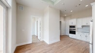Located at 900 New Day Avenue in Montgomery, Texas, this single-story residence offers a well-planned layout comprising a kitchen, bedroom, bathroom, and closet. Warm wood-look flooring runs throughout the home, complementing a clean, neutral color palette that lends a bright and cohesive feel to every room.

The kitchen is a standout feature, outfitted with crisp white shaker cabinetry, matte black hardware, and a full suite of stainless steel appliances including a built-in double wall oven, microwave, cooktop, dishwasher, and refrigerator. A white hexagonal tile backsplash and light countertops complete the polished, contemporary aesthetic.

The bedroom is a comfortable, well-proportioned space filled with natural light from a pair of large black-framed windows that frame views of the surrounding Texas landscape. The room connects conveniently to the bathroom and dedicated closet.

The bathroom features wood-look tile flooring, a glass-enclosed walk-in shower with marble-style tile surround, and accessibility-friendly grab bars, reflecting a thoughtful and functional design. Recessed lighting and a ceiling fan contribute to the home's modern, move-in-ready appeal throughout. The overall ambiance is clean, contemporary, and inviting.