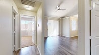 Located along North Scottsdale Road in Phoenix, Arizona, this single-story unit offers a clean, modern aesthetic with consistent wood-style flooring running throughout the main living areas. The open layout connects the living and dining spaces seamlessly, with crown molding adding a refined architectural detail to the ceilings. A ceiling fan keeps the living area comfortable, while a sliding glass door fitted with vertical blinds provides access to the outdoors and fills the space with natural light. Additional windows with blinds further brighten the interior.

The kitchen is well-appointed with white shaker-style cabinetry, light quartz countertops, and a gray subway tile backsplash. Stainless steel appliances—including a range, microwave, dishwasher, and refrigerator—complete the functional and contemporary setup. The layout allows for a clear sightline into the adjoining living areas.

The bathroom features a full tub-shower combination with white tile surround, a white vanity with a speckled stone countertop, and a mirrored medicine cabinet. The entryway includes built-in shelving for added storage convenience. Neutral wall tones and consistent finishes throughout contribute to a cohesive and inviting overall ambiance.