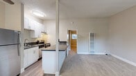Located at 1038 Second St in Lafayette, CA, this single-floor, one-bedroom, one-bathroom unit offers a practical and well-organized layout. The open-concept design connects the kitchen and living area seamlessly, creating a functional flow throughout the space. The kitchen is outfitted with white shaker-style cabinetry, dark countertops, stainless steel appliances including a refrigerator and electric range, and a built-in counter-height desk area — ideal for a workspace. A peninsula with a dark countertop defines the kitchen boundary while maintaining visual openness to the living area. Wood-look flooring runs through the kitchen and dining zone, transitioning to soft carpet in the living and bedroom areas. A ceiling fan with a light fixture provides both comfort and illumination to the main living space. The bedroom offers a comfortable footprint with plush carpeting, neutral walls, and a sliding-door closet with built-in shelving. The bathroom features a full tub-shower combination with tiled surround, a small window for natural light and ventilation, light wood-look flooring, and brushed nickel fixtures. A wall-mounted HVAC unit in the living area ensures year-round climate control. The overall aesthetic is clean, neutral, and move-in ready.
