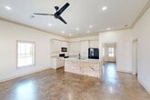 Located at 5241 Rue de Chateau in Alexandria, Louisiana, this single-story 2-bedroom, 2-bathroom home offers a clean, modern aesthetic throughout its efficiently designed floor plan. Polished concrete floors run consistently through the living areas, bedrooms, and bathrooms, providing a durable and stylish foundation. The living area features crown molding, ceiling fans, recessed lighting, and multiple windows that invite ample natural light and neighborhood views.

The kitchen is a standout feature, showcasing white shaker-style cabinetry extending to the ceiling, granite countertops with subtle veining, and a distinctive brick-accented island with a built-in sink. Black appliances, including a range, microwave, and refrigerator, provide a bold contrast to the crisp white cabinetry.

The primary bedroom is a comfortable, well-proportioned retreat with a ceiling fan and direct access to a hallway leading to closet and bathroom facilities. The second bedroom also features a ceiling fan and a bright window with outdoor views. Both bathrooms are finished with granite-topped vanities, white shaker cabinetry, and matte black hardware. One bathroom includes a full tub-shower combination. A dedicated closet offers dual shelving for organized storage. The attached garage includes an automatic opener and attic access panel, completing this practical and tastefully finished home.