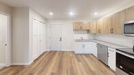 Located on Lakeland Drive NE in Willmar, Minnesota, this one-bedroom, one-bathroom unit offers a thoughtfully designed layout with modern finishes throughout. Warm-toned hardwood-style flooring runs continuously through the main living areas, creating a cohesive and inviting ambiance.

The open kitchen and living room area is a standout feature, showcasing a full suite of stainless steel appliances — including a refrigerator, electric range, over-the-range microwave, and dishwasher. Light wood upper cabinetry is paired with crisp white lower cabinets and complemented by a herringbone tile backsplash and light stone countertops. Recessed lighting adds a clean, modern touch. A sliding glass door opens to a private balcony, bringing in natural light and providing pleasant outdoor views of the surrounding greenery.

The bedroom is a comfortable, well-proportioned room featuring a window with outdoor views and hardwood-style flooring. The bathroom offers a clean, neutral palette with tile flooring, a soaking tub, wood-toned vanity with modern hardware, and matte black accents.

A dedicated laundry room includes a full-size washer and dryer with shelving for added storage. The unit also features ample closet space, completing this functional and attractively finished home.