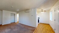 Located at 8435 SE Insley St in Portland, Oregon, this single-floor, three-bedroom, one-bathroom home offers a practical and functional layout. The living area features a textured ceiling, plush carpeting, and transitions to hardwood-style flooring toward the kitchen. A wall-mounted mini-split system provides efficient climate control, while a ceiling fan in the kitchen area adds additional comfort. The kitchen is equipped with a freestanding range. The spacious primary bedroom is notably generous in size, featuring carpet flooring, a closet, and a textured ceiling. The two additional bedrooms are carpeted as well, each with clean white walls, baseboard heating, and ample natural light from windows. One of the secondary bedrooms includes a closet with built-in shelving. A hallway connects the bedrooms to the shared bathroom, which is finished with neutral tile surround on the tub/shower combo, a mosaic accent border, a vanity with wood-toned cabinetry, and hardwood-style flooring. Two closets provide additional storage throughout the home. The overall layout is efficient, with a straightforward flow between rooms, neutral finishes throughout, and a clean, move-in-ready aesthetic.