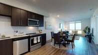 This single-floor residence on Bayfront Boulevard in Hercules, California, presents a thoughtfully designed open-concept layout that seamlessly connects the kitchen, dining, and living areas. The kitchen is a standout feature, outfitted with dark espresso cabinetry, light quartz countertops, a subway tile backsplash, and a full suite of stainless steel appliances including a French door refrigerator, electric range, built-in microwave, and dishwasher. Warm wood-tone flooring runs throughout the main living areas, contributing to a cohesive and contemporary aesthetic.

The living room is bright and inviting, anchored by a large window that frames sweeping outdoor views, filling the space with natural light. The dining area flows naturally between the kitchen and living room, making the layout well-suited for both daily living and entertaining.

The bedroom features plush carpeting, a walk-in closet, and a large window offering expansive views of the surrounding landscape. The bathroom is finished with matching dark cabinetry, quartz countertops, a glass-enclosed shower, and wood-look flooring, maintaining design consistency throughout. In-unit laundry is also present, adding everyday convenience to this well-appointed residence.