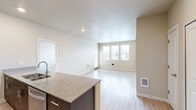 Located in Portland, OR, this 1-bedroom, 2-bathroom residence offers a thoughtfully designed single-floor layout with modern finishes throughout. The open-concept kitchen and living area serves as the heart of the home, featuring light wood-style flooring, recessed lighting, and generous natural light streaming through large windows with views of the surrounding neighborhood. The kitchen is equipped with stainless steel appliances, including a refrigerator, range, and microwave, complemented by dark espresso cabinetry, granite countertops, and a peninsula with a double undermount sink — ideal for both cooking and casual dining. The living area is bright and airy, with a glass-panel door providing direct outdoor access. The bedroom offers a comfortable footprint with soft wall-to-wall carpeting, dual windows for natural light, and convenient access to two closets. The two bathrooms are finished with wood-style flooring, dark vanity cabinetry with granite countertops, and chrome fixtures; one features a walk-in shower stall, and the other includes a bathtub. Clean neutral tones and contemporary detailing create a cohesive, move-in-ready atmosphere throughout the entire space.