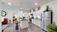 This single-floor residence offers a thoughtfully designed layout that balances comfort and functionality. The kitchen serves as a central highlight, showcasing crisp white shaker-style cabinetry extending to the ceiling, dark granite countertops, a subway tile backsplash with under-cabinet lighting, stainless steel appliances, and a central island with bar seating — ideal for both cooking and casual dining. Hardwood-style flooring runs throughout the main living areas, adding warmth and cohesion to the space. The living room is bright and welcoming, with large windows that invite natural light, a sliding door providing outdoor access, and a ceiling fan overhead. The bedroom is a calm retreat, featuring plush carpeting and ample room for furnishings. The bathroom is neatly finished with white cabinetry, granite countertops, tile flooring, and a shower-tub combination. A dedicated in-unit laundry area with a full-size washer and dryer adds everyday convenience. The overall design aesthetic is clean and contemporary, with neutral tones and modern finishes creating a cohesive and inviting atmosphere throughout.