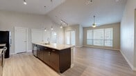 Located in Austin, TX 78750, this well-appointed 3-bedroom, 2-bathroom residence at Arbol offers a thoughtfully designed single-floor layout. The open-concept kitchen and living area forms the heart of the home, highlighted by soaring vaulted ceilings, track lighting, and pendant lights over a large granite-topped kitchen island with an undermount sink. Rich dark-espresso cabinetry extends to the ceiling and is paired with a classic white subway tile backsplash and a full suite of stainless steel appliances, including a range, microwave, and French door refrigerator. Light wood-style flooring flows throughout the main living areas, complementing the neutral warm-toned walls. The spacious living room is bathed in natural light from large windows and a set of French doors, and is finished with a ceiling fan overhead. The primary bedroom suite features its own bathroom with granite countertops, dark cabinetry, a walk-in closet, and light wood flooring. The secondary bedrooms offer plush carpeting, ceiling fans, and generous natural light. A second full bathroom mirrors the refined finishes seen throughout the home. Two hallways connect the rooms efficiently, and a dedicated closet provides additional storage.