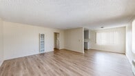 Located on Laurel Canyon Boulevard in the Pacoima neighborhood of Los Angeles, this single-story, 3-bedroom, 1-bathroom home offers a practical and comfortable layout. The open-concept living room and kitchen area is bright and airy, featuring light wood-look laminate flooring, a textured ceiling, and vertical blind-covered windows that allow natural light to fill the space. A wall-mounted heater unit adds a functional touch to the living area, which also includes a convenient built-in closet.

The galley-style kitchen is efficiently designed with ample gray cabinetry lining both walls, light stone countertops, a gas range, and a stainless steel sink — all set on matching wood-look flooring.

The three bedrooms are carpeted in a warm tan tone, offering a cozy feel. The primary bedroom is generously sized and features vaulted ceiling details, a large window with vertical blinds for natural light, and a spacious closet. The additional bedrooms are similarly bright, each with windows and closet space.

The full bathroom is well-appointed with a warm wood vanity, granite countertop, an undermount sink, a large mirror, and a tub-shower combo with sliding glass doors, all set on wood-look flooring. A hallway connects the bedrooms to the main living areas, completing this functional single-floor layout.