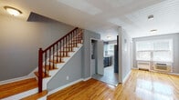 Located at 36 Welcher Ave in Peekskill, NY, this two-floor home combines classic charm with modern updates. The main level welcomes you with gleaming hardwood floors that flow throughout, neutral gray walls, and natural light from well-placed windows. The spacious living area offers a warm, open feel with a radiator heating system and direct access to the front entry. The kitchen is thoughtfully updated, featuring dark shaker-style cabinetry, white quartz countertops, a marble-style tile backsplash, stainless steel appliances including a gas range, and a stainless steel sink. A convenient half bath with a pedestal sink is also found on this level, alongside in-unit washer/dryer hookups tucked neatly off the main hallway. A staircase with a classic wood banister and painted balusters leads to the upper floor, where the hardwood flooring continues. The bedrooms are generously sized, each painted in soft gray tones, with windows offering outdoor views, wall-unit climate control, and ample closet space. The full bathroom on the upper level features large-format tile walls, a soaking tub with a tub filler, a modern floating vanity, and a privacy window, offering a clean, contemporary aesthetic throughout.