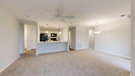 This single-story residence at 2828 Warm Springs Rd in Columbus, Georgia offers a clean, contemporary design highlighted by a neutral color palette and an abundance of natural light throughout. The open-concept living and dining area is generously proportioned, featuring plush carpeting, ceiling fans, and pendant lighting that adds a polished touch. Two sets of sliding glass doors connect the living space to an outdoor balcony, inviting views of the surrounding greenery and enhancing the sense of openness.

The kitchen is efficiently designed with white cabinetry, white quartz-style countertops, a classic subway tile backsplash, and black appliances including a refrigerator, range, and over-the-range microwave. A raised breakfast bar peninsula separates the kitchen from the living area, making it ideal for casual dining and entertaining.

The bedrooms are carpeted and well-lit by windows with blinds, each equipped with a ceiling fan. The bathroom features a wide vanity with white cabinetry, a large mirror, and wood-look flooring that extends into the hallway. A dedicated laundry area with wire shelving and utility hookups adds practicality, while recessed lighting and wood-look flooring in the utility spaces complete the home's cohesive, modern aesthetic.