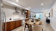 Located at 10375 Washington Blvd in the heart of Culver City, this well-appointed 1-bedroom, 1-bathroom residence offers a thoughtfully designed open-concept layout across a single floor. Light wood flooring flows throughout, tying together each space with a warm, cohesive aesthetic.

The kitchen is a standout feature, showcasing rich walnut cabinetry paired with crisp white upper cabinets and quartz countertops. A stainless steel appliance suite includes a gas cooktop, built-in oven, dishwasher, and French door refrigerator, complemented by a stainless range hood and open floating shelves for display. A round dining table sits adjacent to the kitchen, creating a natural transition to the open living area.

The living room is bright and inviting, with recessed lighting, neutral tones, and a sliding glass door that opens to a private balcony — bringing in natural light and an indoor-outdoor connection. The bedroom features a tray ceiling with integrated lighting, a window with outdoor views, and direct access to a closet. The bathroom is finished with large-format tile flooring, a floating vanity with a dark wood countertop, and clean white cabinetry. A hallway connects the rooms, completing this efficiently designed and stylish Culver City residence.