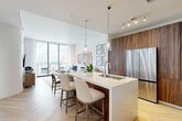 Located at 201 SE Sixth Ave in the heart of Fort Lauderdale, this thoughtfully designed one-bedroom, one-bathroom residence offers a refined living experience with upscale finishes throughout. The open-concept living and kitchen area is anchored by floor-to-ceiling sliding glass doors that flood the space with natural light and open to a private balcony showcasing sweeping city views. Light-toned herringbone hardwood flooring flows seamlessly throughout, lending warmth and elegance to every room.

The kitchen is a standout feature, boasting rich walnut cabinetry that spans floor to ceiling, a striking marble-finish waterfall island with bar seating, pendant lighting, stainless steel appliances, and a sleek range hood. The adjacent living area offers a comfortable, airy atmosphere ideal for relaxing or entertaining.

The bedroom is a serene retreat, highlighted by a soft blue accent wall, large windows with city views, and herringbone flooring that continues throughout. A well-organized walk-in closet with custom built-in shelving provides ample storage. The bathroom features warm wood vanity cabinetry, a clean white countertop with an undermount sink, and polished chrome fixtures, all set against a bright, crisp backdrop. Every detail reflects a modern coastal aesthetic.