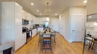 Located at 9235 Senator Royall Dr. in Charlotte, NC, this single-floor residence offers a thoughtfully designed open-concept layout with modern finishes throughout. The kitchen is a standout feature, equipped with white shaker cabinetry, dark quartz countertops, stainless steel appliances, a classic subway tile backsplash, and a central island with pendant lighting — ideal for both cooking and casual dining. Warm hardwood-style flooring flows seamlessly through the kitchen and dining area, enhancing the sense of openness. The living room is bright and welcoming, with soft neutral walls, recessed lighting, and space for comfortable furnishings and wall art. The bedrooms are carpeted and well-sized, each featuring ceiling fans, generous natural light from large windows, and direct access to bathrooms. The primary bathroom is particularly well-appointed, with a dual-sink vanity featuring white cabinetry and dark countertops, a large frameless glass walk-in shower with tile surround, and wood-look flooring. A secondary bathroom offers similarly clean, modern finishes. Throughout the residence, the design strikes a balance between functionality and contemporary style, creating a cohesive and comfortable living environment.