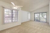 This single-floor residence offers a clean, well-organized layout designed for comfortable everyday living. The spacious living area immediately draws attention with its vaulted ceilings, a ceiling fan with light fixture, and plush wall-to-wall carpeting. Large windows fitted with vertical blinds flood the space with natural light, while a sliding glass door opens to an outdoor balcony overlooking lush greenery, creating a seamless indoor-outdoor connection.

The kitchen is efficiently designed with white cabinetry — including a tall pantry cabinet — granite-style countertops, a stainless steel sink, and wood-look vinyl flooring. Ample counter and storage space make it highly functional.

The bedrooms are carpeted and bright, each featuring windows with vertical blinds that invite natural light. Vaulted ceilings in the primary bedroom enhance the sense of spaciousness, and a closet with sliding doors provides convenient storage. An additional bedroom offers a similarly airy feel with a large window and closet access.

Two bathrooms serve the residence. Each features white cabinetry, granite-style countertops, a single-basin sink, and wood-look vinyl flooring. One bathroom includes a shower-tub combination with a window above, while the other features a well-lit vanity mirror. Together, the rooms create a cohesive, light-filled living environment.