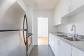 Located at 10 Garfella Dr in Toronto's northwest end, this 2-bedroom, 1-bathroom unit offers a thoughtfully laid-out single-floor plan with a clean, bright aesthetic throughout. The living room is one of the standout spaces, featuring warm parquet wood flooring in a classic herringbone-style pattern and a large window that fills the room with natural light while offering open views of the surrounding neighbourhood and greenery. The kitchen has been updated with white shaker-style cabinetry, grey laminate countertops, a double stainless steel sink with a modern pull-down faucet, and stainless steel appliances, including a full-size refrigerator. Tile flooring completes the kitchen's clean, functional aesthetic. Both bedrooms continue the parquet flooring theme, each featuring windows with baseboard heating units beneath and ample wall space. The primary bedroom includes a double-door closet for generous storage. The bathroom is finished with classic white subway tile surrounding a full bathtub and shower combination, lending a timeless, clean look. A hallway and entrance area connect the rooms efficiently, contributing to the unit's practical and cohesive flow throughout.