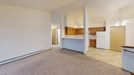 Located at 877 Arthur Dr in Milton, Wisconsin, this single-floor unit offers a functional and straightforward layout suited for comfortable everyday living. The open-concept living and kitchen area serves as the heart of the space, where a peninsula breakfast bar separates the two zones while maintaining visual connectivity. The kitchen is equipped with warm oak cabinetry, white appliances including a range and full-size refrigerator, light tile flooring, and a pendant light fixture overhead. Baseboard heating is present throughout.

The living area features neutral carpet, a vaulted ceiling, and sliding glass doors that lead to an outdoor deck, providing natural light and outdoor access. Multiple bedrooms are carpeted and finished with neutral walls, wood-trimmed doors, and windows that bring in natural light with views of the surrounding neighborhood. Baseboard heaters are present in the bedrooms as well.

The bathroom includes tile flooring, an extended vanity with a single sink, a large mirror, and a separate toilet and tub area. A dedicated in-unit laundry space accommodates a full-size washer and dryer side by side, adding practical convenience. Overall, the unit maintains a clean, neutral palette throughout.