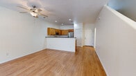 This two-story residence offers a practical and well-organized layout spread across two floors. The main level features an open-concept living room and kitchen area finished with light hardwood-style flooring throughout. The kitchen is equipped with warm honey-toned wood cabinetry, dark countertops, a double-basin stainless steel sink, and a full suite of stainless steel appliances including a range, microwave, and refrigerator. A peninsula-style counter separates the kitchen from the living area, which is outfitted with a ceiling fan and recessed lighting. A convenient half-bath with a pedestal sink and oval mirror is also located on the main floor.

The upper level houses both bedrooms, each featuring plush carpet flooring and ceiling fans. The spacious primary bedroom includes an en-suite bathroom and ample room for furnishings. The second bedroom is bright and comfortable, with a window bringing in natural light. A full bathroom on this floor features a wood-toned vanity with dark countertop, a tub-shower combination, and hardwood-style flooring. Two closets provide generous storage throughout the home. The textured ceilings and neutral color palette give the entire space a clean, move-in-ready appearance.