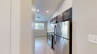 Located at 2410 N Cherry St in Spokane Valley, WA, this two-bedroom, one-bathroom unit offers a well-planned single-floor layout designed for comfortable everyday living. The kitchen is a standout feature, equipped with stainless steel appliances including a refrigerator, range, and over-the-range microwave, complemented by rich dark cabinetry and marble-style countertops. Light wood-style flooring flows throughout the kitchen and living areas, adding a clean, modern aesthetic. A galley-style kitchen passage leads to an in-unit laundry area, providing added convenience. The living room opens to a private balcony through a sliding glass door, filling the space with natural light and offering pleasant outdoor views of surrounding trees. Both bedrooms feature plush carpeting, neutral-toned walls, and windows that bring in natural light, creating restful retreats. The primary bedroom offers a generous footprint with dedicated closet space. The full bathroom includes a single-sink vanity with dark cabinetry and a marble-style countertop, a tub-shower combination, and wood-style flooring that ties the space together. Recessed lighting and vaulted ceiling details in key areas enhance the overall sense of openness throughout the unit.
