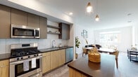 Located at 4949 Baltimore Dr in La Mesa, California, this single-story residence offers a thoughtfully designed living space with a clean, contemporary aesthetic. The open-concept layout seamlessly connects the kitchen and living area, creating a cohesive and functional flow throughout the home. The kitchen is well-appointed with stainless steel appliances, including a gas range, built-in microwave, dishwasher, and a side-by-side refrigerator with an in-door water and ice dispenser. Warm wood-toned lower cabinetry is paired with sleek dark upper cabinets and dark countertops, complemented by a tiled backsplash and open display shelving. A kitchen island with a matching dark countertop provides additional workspace and casual dining. The living area is bright and welcoming, featuring large windows that invite natural light and offer views of nearby palm trees and the surrounding neighborhood. The bedroom continues the light-filled theme with a generously sized window framing outdoor greenery, providing a calm and restful retreat. The bathroom is finished with a wood-grain vanity, dark countertop, an undermount sink, and a large mirror, maintaining the modern design language found throughout the home. Durable wood-look flooring flows through the main areas, tying the space together with a warm yet modern sensibility.