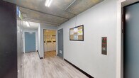 Located at 5447 White Oak Ave in Encino, California, this single-floor common area facility offers a range of practical amenities within a distinctively designed interior. The hallway is the visual centerpiece of the space, featuring a striking hand-painted underwater mural that spans the length of the corridor. The artwork depicts marine life including a shark, fish, and lush seagrass rendered across exposed concrete block walls, creating an immersive and memorable aesthetic. Light wood-style flooring runs throughout, complementing the industrial-style exposed ceiling with fluorescent strip lighting and visible utility conduits. The corridor provides access to multiple areas, including a dedicated locker room equipped with tall dark metal lockers with electronic locks, continuing the ocean mural theme. A bulletin board and fire safety panel are conveniently positioned near the elevator, which offers accessible floor navigation. The shared laundry room is well-appointed with multiple top-load washing machines, a dryer, and a folding counter, all maintained in a clean, bright environment with recessed lighting and posted operating instructions. This facility combines functional amenities with creative design, making it a well-equipped and visually engaging shared space.