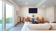 This two-story home in Oak Grove, Missouri offers a thoughtfully designed layout spread across two floors. The main level features a bright, open living room with wood-look flooring, recessed lighting, and a sliding glass door that floods the space with natural light and provides views of the outdoors. The kitchen is outfitted with light wood cabinetry, white quartz countertops, a subway tile backsplash, and a full suite of stainless steel appliances, creating a clean and functional cooking space. A hallway with the same wood-look flooring leads seamlessly between rooms, flanked by a carpeted staircase with sleek black iron balusters and a white railing. Upstairs, three bedrooms offer comfortable retreats, each with plush carpet, ceiling fans, and ample closet space. The primary bedroom includes a well-sized closet and an en-suite bathroom featuring a dual-sink vanity with wood cabinetry, black fixtures, a large mirror, and wood-look tile flooring. Additional bathrooms mirror the home's consistent aesthetic, featuring wood-toned vanities, tub-shower combinations, and clean white finishes. With four total bathrooms and two dedicated closets, this home balances practicality and modern style throughout.
