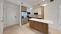 This single-story, 2-bedroom, 2-bathroom residence at 4970 SW 124th Ave offers a clean, contemporary design throughout. The open-concept kitchen serves as a focal point of the living area, showcasing a two-tone cabinetry scheme that pairs warm wood-grain lower cabinets with crisp white upper cabinets. A large island with a white quartz countertop provides ample workspace and casual dining space. Stainless steel appliances, including a French door refrigerator, electric range, microwave, and dishwasher, complete the kitchen. A subway tile backsplash and pendant lighting add refined detail.

Light-toned large-format tile flooring runs throughout the unit, enhancing the bright, airy atmosphere. The bedrooms are generously proportioned, featuring neutral walls and windows that allow natural light to filter in, with views of the surrounding landscape.

The primary bathroom features a sleek vanity with wood-toned cabinetry, a white quartz countertop, an undermount sink, and a glass-enclosed shower with floor-to-ceiling tile. The secondary bathroom includes a soaking tub with shower combination. A walk-in closet provides practical storage. The overall ambiance is modern, clean, and move-in ready.