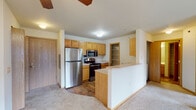 Located at 202 Prairie Heights Dr in Verona, Wisconsin, this single-floor residence offers a well-organized, open-concept layout designed for comfortable everyday living. The spacious living room is finished with soft wall-to-wall carpeting and features a ceiling fan with integrated lighting. A wall-mounted air conditioning unit and baseboard heating provide year-round climate control, while a sliding glass door opens to an outdoor balcony, allowing natural light to fill the room. The kitchen is thoughtfully designed with warm honey-toned oak cabinetry, stainless steel appliances including a refrigerator, range, and over-the-range microwave, and durable wood-look flooring. A peninsula counter with breakfast bar seating separates the kitchen from the living area, and a dedicated pantry with wire shelving offers generous storage. A bedroom provides a quiet retreat with carpeted flooring, a window with natural views, and baseboard heating. The full bathroom is finished with wood-look flooring and features an extended oak vanity with ample counter space and under-sink storage, a large mirror, and a full soaking tub with shower. A stacked washer and dryer unit tucked into a dedicated closet adds in-unit laundry convenience. The overall palette of neutral tones and warm wood accents creates a clean, functional living environment.