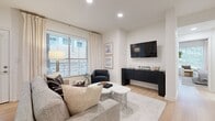 This single-story residence showcases a cohesive contemporary design characterized by a neutral palette, light hardwood flooring, and recessed lighting throughout. The open-concept living area serves as the heart of the home, featuring large windows with elegant linen draping that invite abundant natural light. French doors provide direct outdoor access, further enhancing the bright, airy atmosphere. A wall-mounted television, sleek dark credenza, and organic-shaped marble coffee table contribute to the room's refined aesthetic.

Adjacent to the living area, a dedicated dining nook accommodates a round marble-top table, complemented by a full-length mirror and lush indoor greenery that add depth and character to the space.

The kitchen is efficiently designed with white shaker cabinetry extending to the ceiling, quartz countertops, a herringbone tile backsplash, and stainless steel appliances. A peninsula with an undermount sink and matte black fixtures provides seating and additional workspace.

The bedroom is a tranquil retreat bathed in natural light, with views of mature trees outside. It features a spacious walk-in closet with organized built-in storage. The bathroom is finished with white cabinetry, quartz surfaces, matte black hardware, large-format tile flooring, and a glass-enclosed tub-shower combination.