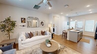 Located at 8901 Brewer Blvd in Fort Worth, TX, this single-story, 2-bedroom, 2-bathroom home offers a thoughtfully designed open-concept layout. The combined living, dining, and kitchen area is bright and welcoming, with warm wood-look flooring, recessed lighting, and a ceiling fan overhead. Large windows dressed with plantation shutters and sheer curtains invite an abundance of natural light. The kitchen stands out with its elongated island featuring a deep undermount sink, crisp white quartz countertops, gray shaker cabinetry, a subway tile backsplash, stainless steel appliances, and elegant pendant lighting. The primary bedroom is a serene retreat with soft neutral tones and direct access to a private en-suite bathroom, which includes a glass-enclosed walk-in shower with large-format tile and a walk-in closet. The second bedroom is comfortably sized with a ceiling fan and natural light from a window. The second bathroom offers a full tub-shower combo with coordinating tile surround. A dedicated laundry room with full-size washer and dryer adds everyday convenience. Additional highlights include three closets, a pantry, and a small outdoor area visible from the home's exterior, completing this efficiently designed and stylishly finished residence.