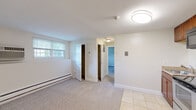 Located at 141 Broadmeadow St in Marlborough, Massachusetts, this single-floor unit offers a functional and straightforward layout with a clean, neutral aesthetic throughout. The entryway features light tile flooring that transitions into wall-to-wall carpeting across the main living areas, creating a warm and cohesive feel. The living space is bright and open, with white walls, white trim, and windows that allow natural light to filter in. Baseboard heating units run along the perimeter of multiple rooms, ensuring efficient warmth throughout the colder New England months. A dedicated hallway connects the main living area to the private rooms, providing a clear and practical flow. The bedroom is a comfortable, carpeted space with a built-in closet featuring a bifold door and direct access to the full bathroom. The bathroom is finished with beige tile surrounding the bathtub and shower, complemented by a white vanity with under-cabinet storage, a mirrored medicine cabinet, and a light fixture above — all set on tile flooring. The unit's overall palette of whites and neutrals gives it a clean, move-in-ready appearance, and its straightforward single-level design makes it easily accessible and navigable.