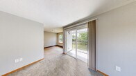 Located on Hidden Creek Loop NE in Keizer, Oregon, this two-bedroom, one-bathroom home offers a functional and comfortable single-floor layout. The living room is generously sized, featuring plush carpeting, neutral gray walls with warm wood baseboards, and a sliding glass door that opens to a private balcony overlooking a lush green outdoor setting — bringing in abundant natural light and a pleasant outdoor connection.

The kitchen and dining area are combined into one efficient space, showcasing warm honey-toned wood cabinetry, gray laminate countertops, and light hardwood-style flooring. White appliances including a range and refrigerator are included, and an in-unit washer and dryer area is conveniently located just off the kitchen.

Both bedrooms are carpeted and feature large windows with wood sill accents that allow ample natural light and views of the surrounding neighborhood and mature trees. The primary bedroom offers a comfortable footprint, while the second bedroom is equally well-appointed with a sliding closet door.

The bathroom features warm wood cabinetry, a gray laminate countertop, an integrated sink, and a mirror — maintaining the cohesive, practical design found throughout the home. Textured ceilings are consistent throughout the space, adding a classic residential character to this well-laid-out Keizer home.