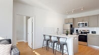 This well-designed 2-bedroom, 2-bathroom residence at 1001 W Elizabeth Ave in Linden, NJ offers a clean, contemporary aesthetic throughout. The open-concept living area seamlessly connects the kitchen, dining, and living spaces, creating an efficient and welcoming environment. Light wood flooring runs throughout the unit, complementing the bright white walls and modern finishes.

The kitchen is a standout feature, equipped with stainless steel appliances including a refrigerator, range, and microwave, paired with taupe shaker-style cabinetry, white quartz countertops, and a subway tile backsplash. A peninsula island with seating provides additional prep space and a casual dining option, illuminated by track lighting above.

Both bedrooms are bright and comfortable, each benefiting from large windows that invite generous natural light and offer outdoor views. The primary bedroom provides a well-proportioned retreat with ample closet space. The unit includes five closets total, ensuring excellent storage throughout.

The two bathrooms feature matching gray vanities with white countertops and wood-look flooring, maintaining the cohesive modern palette. An in-unit laundry room adds everyday convenience. The overall ambiance is bright, clean, and contemporary, making this a practical and stylish residence.