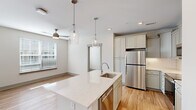 Located at 601 Gilcrest Farm Rd in Wake Forest, NC, this thoughtfully designed two-bedroom, one-bathroom single-floor residence offers a generous and well-appointed living environment. The open-concept kitchen serves as the heart of the home, showcasing a large center island with a quartz countertop, an undermount sink, and elegant glass pendant lighting. Soft gray shaker-style cabinetry extends floor to ceiling, complemented by a herringbone tile backsplash and a full suite of stainless steel appliances, including a refrigerator, microwave, and range. Light hardwood flooring flows throughout the main living areas, enhancing the bright, airy atmosphere created by multiple windows with natural light. The spacious living area features a ceiling fan and access to the outdoors via large glass doors. Both bedrooms are carpeted for comfort and include ceiling fans and windows that bring in natural light. The primary bedroom is generously sized and connects to a walk-in closet outfitted with wire shelving on multiple walls. The bathroom is well-finished, featuring a dual-sink vanity with quartz countertops, gray cabinetry, a large mirror, modern fixtures, and a glass-enclosed shower with hardwood-style flooring. Connected hallways provide a smooth and functional flow throughout the entire residence.
