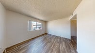 This single-floor unit offers a straightforward and functional layout designed for comfortable everyday living. The main living area is bright and open, featuring durable wood-look flooring that extends throughout the common spaces. A large window allows natural light to fill the room while providing views of the surrounding neighborhood.

The kitchen is well-equipped with warm-toned oak cabinetry offering generous upper and lower storage, light countertops, a double-basin sink, and a full suite of black appliances including a refrigerator, gas range, and dishwasher. The wood-look flooring continues seamlessly into this space, creating a cohesive feel.

The bedrooms are carpeted for added comfort and each feature sliding-door closets with built-in shelving for organized storage. The rooms are bathed in natural light through sizeable windows that look out onto the exterior surroundings. The textured ceiling is consistent throughout the sleeping quarters and living areas, adding a classic residential character.

The bathroom is clean and efficiently designed, featuring a single-sink vanity with oak cabinetry below, a toilet, and a full tub-shower combination with a curtain rod. Wood-look flooring ties the bathroom's aesthetic to the rest of the unit. Overall, the space presents a clean, neutral palette that offers a versatile and move-in-ready environment.